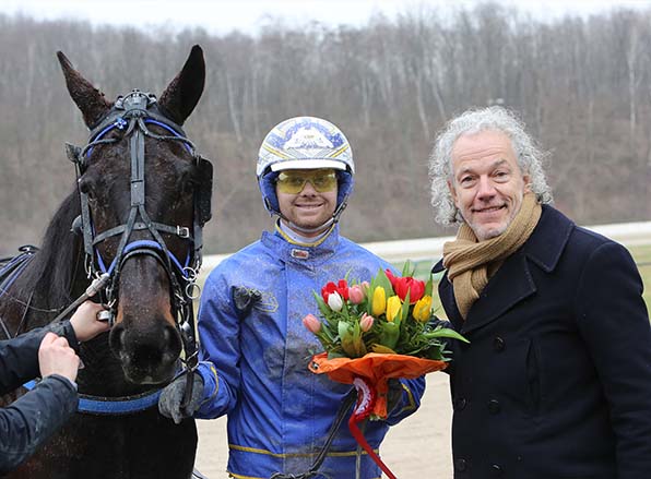Blumen für ein starkes Paar: Rennbahnpräsident Uwe Küster gratuliert Jaap van Rijn und Makalo zu einem beeindruckenden Deutschland-Comeback - © traberfoto-sx